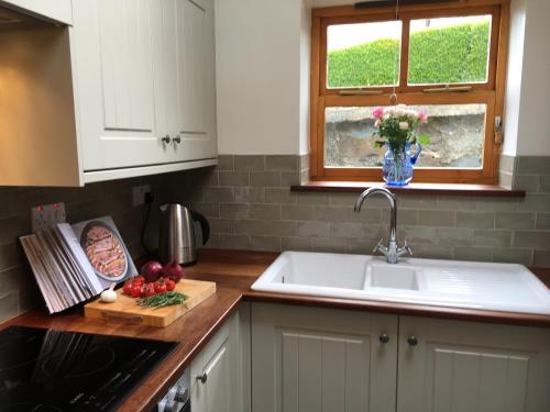 um balcão de cozinha com um lavatório e um vaso de flores em Uwch-Y-Mor em Llanfairfechan