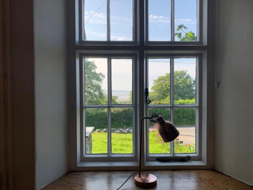 a floor lamp in front of a large window at Uwch-Y-Mor in Llanfairfechan