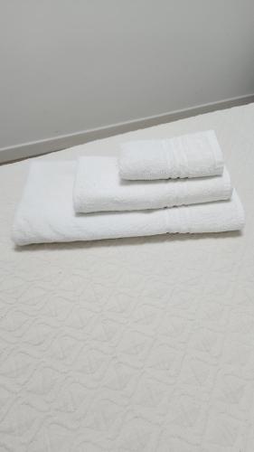 three white towels sitting on top of a bed at CASA CLEO in Udine