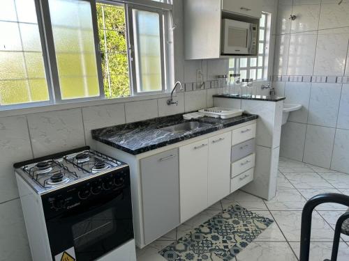 een witte keuken met een fornuis en een wastafel bij Apartamento Bem Localizado in Serra Negra
