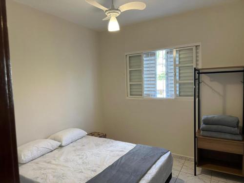 een slaapkamer met een bed en een plafondventilator bij Apartamento Bem Localizado in Serra Negra
