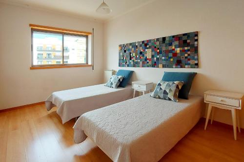 um quarto com 2 camas e uma janela em Sunny Flat Lisbon Oeiras em Quejas