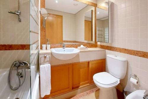 uma casa de banho com um WC, um lavatório e um espelho. em Sunny Flat Lisbon Oeiras em Quejas