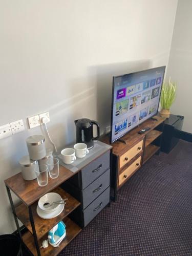 een kamer met een tv en een tafel met kopjes en borden bij Bay view rooms at Mentone Hotel in Weston-super-Mare