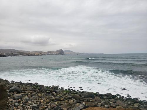 kamienistej plaży z oceanem i łodzi w wodzie w obiekcie Departamento de Playa San Bartolo Ocean Reef - SOL, ARENA Y MAR w mieście San Bartolo