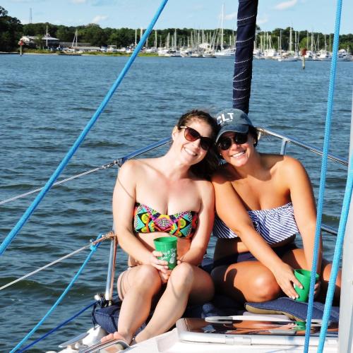 dos mujeres en traje de baño sentadas en un velero en Williamsburg Charter Sails / Let's Go Sail, 