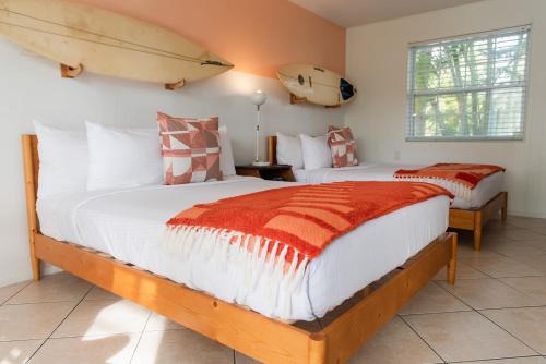 two beds in a room with surfboards on the wall at Seaspray Surf Lodge in Vero Beach