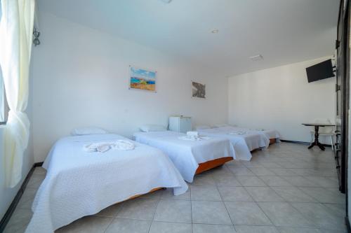 a group of three beds in a room at Hotel Pelican Bay in Puerto Ayora