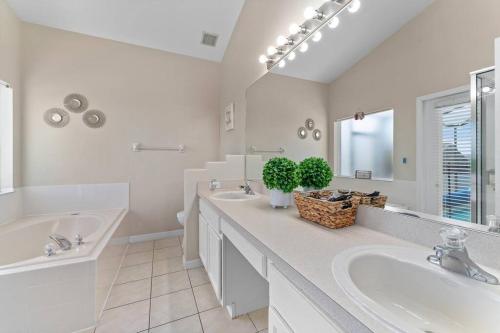 La salle de bains blanche est pourvue de 2 lavabos et d'une baignoire. dans l'établissement Poolside Orlando Oasis, à Orlando