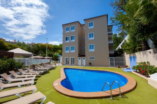einen Pool mit Liegestühlen und ein Gebäude in der Unterkunft Apartamentos Los Dragos del Norte in Puerto de la Cruz
