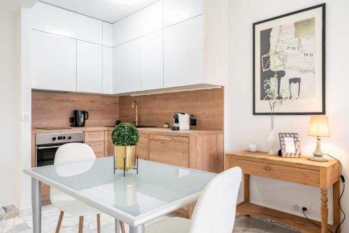 une cuisine avec une table en verre et des placards blancs dans l'établissement Lovely & bright one-bedroom close to the Croisette, à Cannes