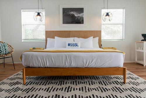 a bedroom with a large bed with a wooden headboard at Seaspray Surf Lodge in Vero Beach