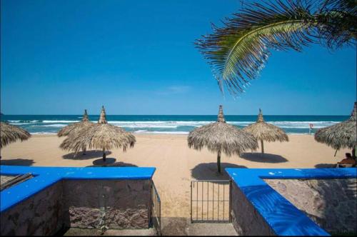 - une plage avec des parasols en paille et l'océan dans l'établissement Quintas del mar Mazatlán, à Mazatlán