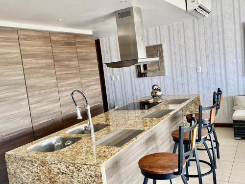 a kitchen with a sink and a counter with stools at Nima Bay, Marina Vallarta in Puerto Vallarta