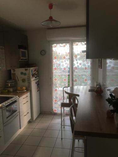 a kitchen with a table and a refrigerator and a window at CHAMBRES in Trappes