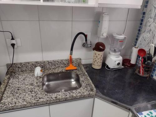 um balcão de cozinha com um lavatório com uma escova laranja em 100 m da praia elevador garagem e portao automático em Mongaguá