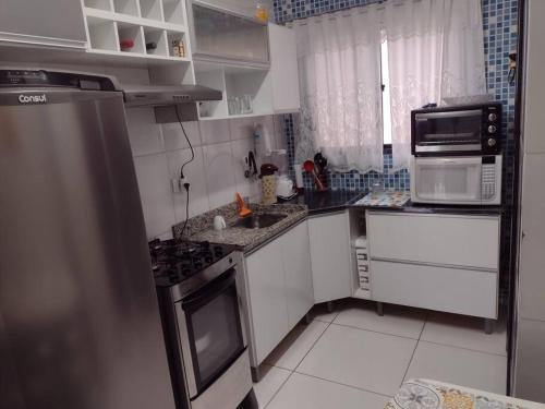 uma cozinha com um lavatório e um fogão forno superior em 100 m da praia elevador garagem e portao automático em Mongaguá