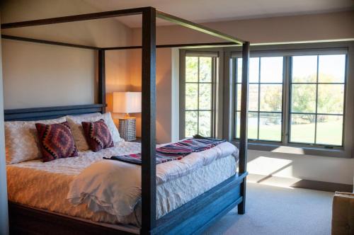Songbird Ranch - Luxury 8 BR Home في دريغس: غرفة نوم مع سرير مظلة في غرفة مع نوافذ
