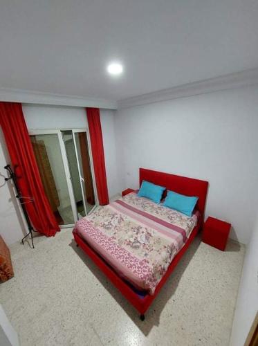 ein Schlafzimmer mit einem roten Bett mit blauen Kissen in der Unterkunft Appartement luxe in El Aouina