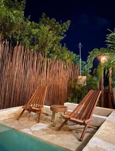 two wooden benches sitting next to a swimming pool at Cssa Kareli Holbox in Holbox Island