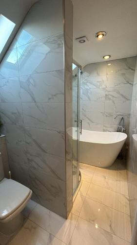 a bathroom with a shower and a tub and a toilet at Castlebar in Great Singleton