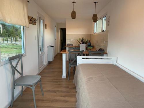 a room with a bed and chairs and a kitchen at La Carmela Container house's in Esquel