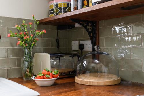 a kitchen counter with a bowl of strawberries and a glass container at Uwch-Y-Mor in Llanfairfechan