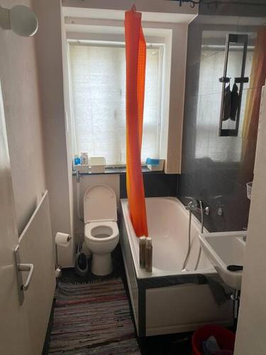 an orange shower curtain in a bathroom with a toilet at Exquisite Berlin Apartment in Berlin