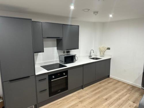 uma cozinha com armários a preto e branco e um micro-ondas em Luxury 2 Bedroom Apartment Located In Birmingham City Centre em Birmingham