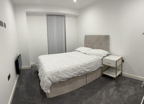 um quarto branco com uma cama e uma mesa de cabeceira em Luxury 2 Bedroom Apartment Located In Birmingham City Centre em Birmingham