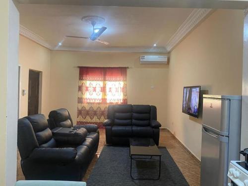 a living room with black leather furniture and a television at Izzy Guest House in Brikama