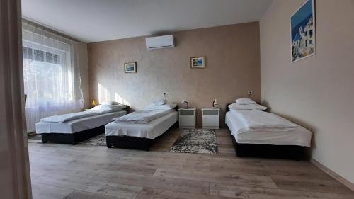 a room with three beds and a window at Alexander apartman in Gyula