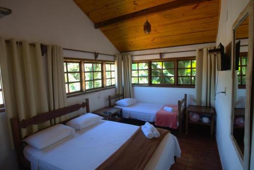 a room with two beds and two windows at Pousada Sobradinho in Tiradentes