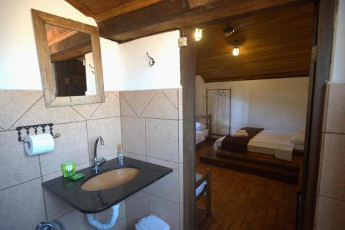 ein Bad mit einem Waschbecken und ein Bett in einem Zimmer in der Unterkunft Pousada Sobradinho in Tiradentes