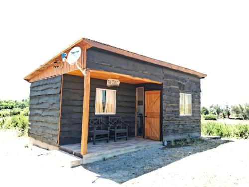 a small log cabin with a porch and chairs at Cabañas Vista Horizonte in El Durazno