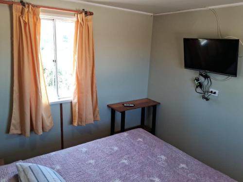 1 dormitorio con 1 cama y TV en la pared en Cabañas Vista Horizonte, en El Durazno