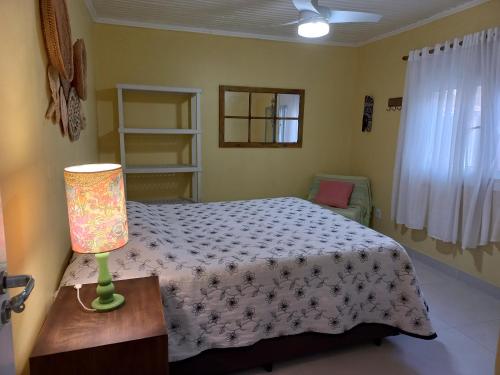 a bedroom with a bed and a lamp on a table at Casa em Atlântida com Piscina in Xangri-lá