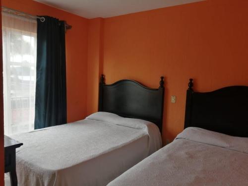 2 letti in una camera con parete arancione di HOTEL VILLA TANCITARO 