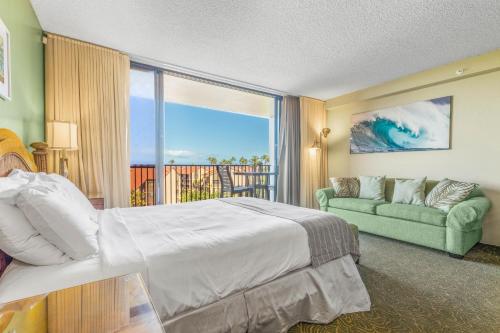 a bedroom with a bed and a couch and a window at Kaanapali Shores 640 in Kahana