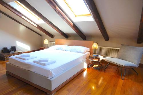 a bedroom with a large white bed and a chair at Politecnico di Torino - Design Suite Hydrangea - Grand Maison in Turin