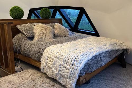 a bedroom with a bed with pillows and a window at Domo en el rincón del paraíso in Ranco