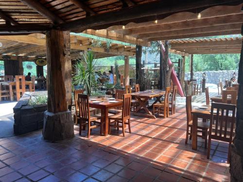a restaurant with wooden tables and chairs on a patio at Cabañas La Calchona in Melocotón