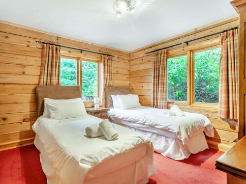 2 łóżka w pokoju z drewnianymi ścianami i oknami w obiekcie 3 Bed in Inverness 86998 w mieście Foyers