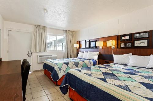 ein Hotelzimmer mit 2 Betten und einem Tisch in der Unterkunft Temple View Inn in Ogden
