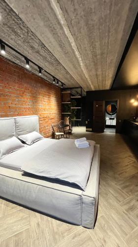 een groot bed in een kamer met een bakstenen muur bij Люкс в стиле LOFT in Pavlodar
