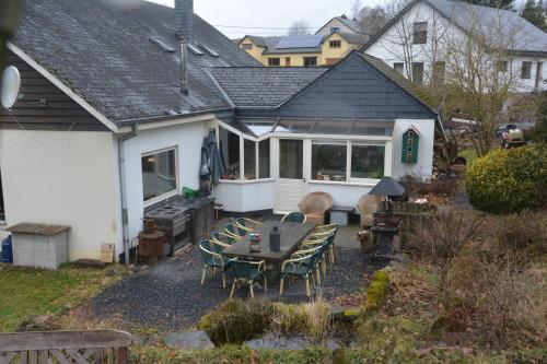 a house with a table and chairs in the yard at B&B La Source Houffalize in Houffalize
