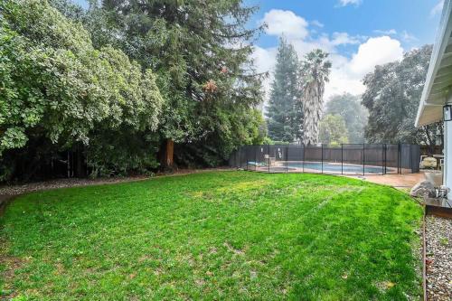 a yard with a fence and a tennis court at The Charming Home with a Pool in Yuba City