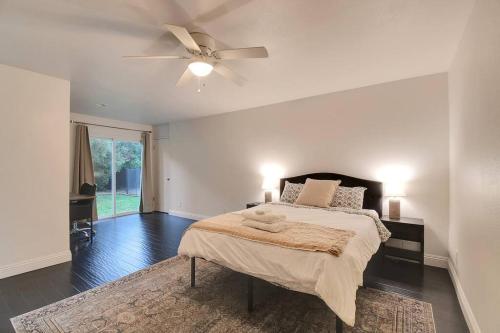 a white bedroom with a bed and a ceiling fan at The Charming Home with a Pool in Yuba City