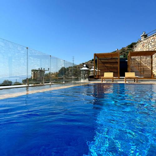 a swimming pool with blue water and two benches at Mesibu Bungalow 