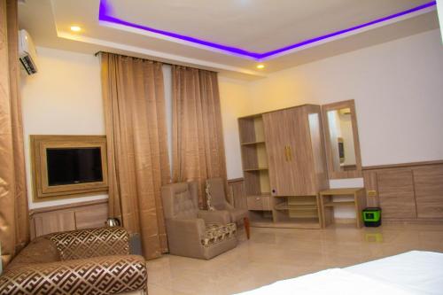 a room with a bed and a tv and a chair at Emperor Melanie Hotels in Akwa